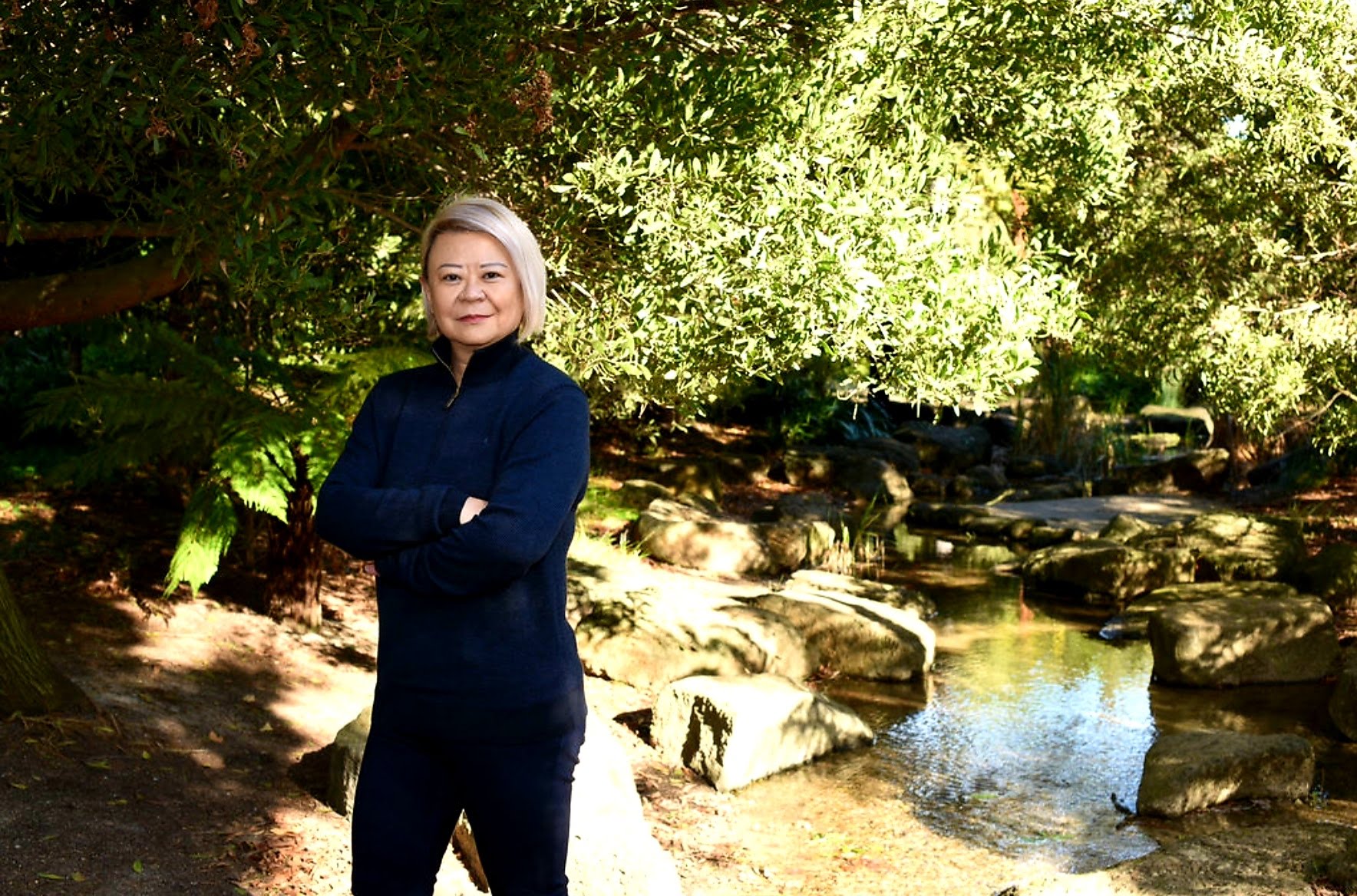 Cassandra Lee wearing navy beside a garden pond